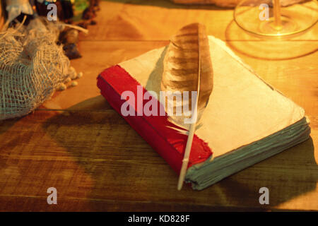 Feather and old book on wooden table closeup Stock Photo