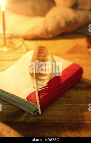 Old book with feather on wooden table Stock Photo