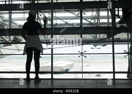 Silhouette of a young woman look out of the window at airport say good bye to her family Stock Photo