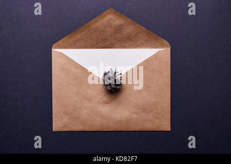 decoration for christmas. browm envelope and pine cone painted in silver over blue background Stock Photo