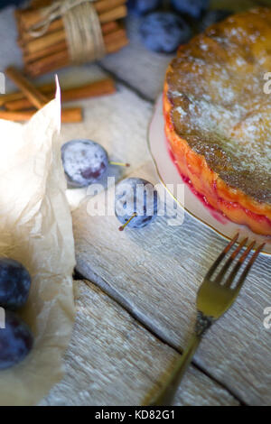 rustic plum cake with knife and fork on white wooden background. Stock Photo