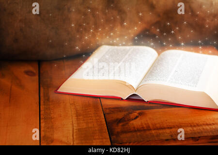 Old open book with magic light on wooden table Stock Photo