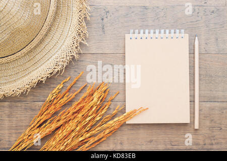 Blank notebook with straw hat and dried flower on wooden background, Top view autumn concept Stock Photo