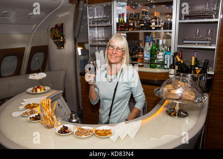 Air Travel Emirates Airbus A380 aircraft, tourist with drink behind Business Class cabin bar Stock Photo