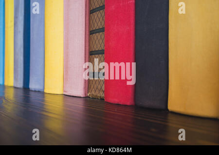 Books in colorful covers stand on wooden shelf Stock Photo