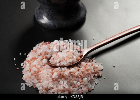 Pink Himalayan Salt Pile With Brown Wood Spoon and Mortar Close-up Stock Photo