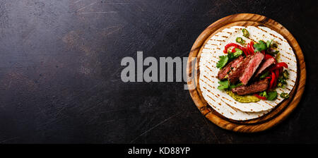 Grilled Beef steak Fajitas taco tortillas with green salsa and bell pepper on dark background copy space Stock Photo