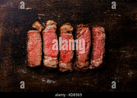 Slices of grilled meat barbecue steak Rib eye medium rare on dark metal background Stock Photo
