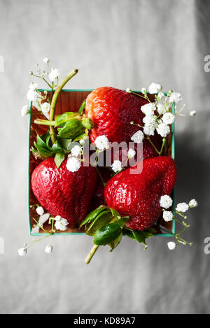 Basket of strawberries and flowers on a linen. Stock Photo