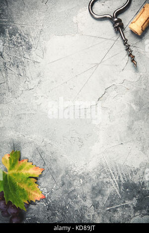Top view of an old cork screw and grape leaf on gray concrete background with space for text.  A vertical design template for a tasting invitation or Stock Photo