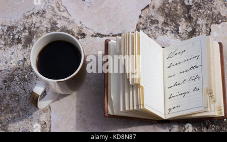 coffee mug and a small notebook with handwritten text about following your dreams diary Stock Photo