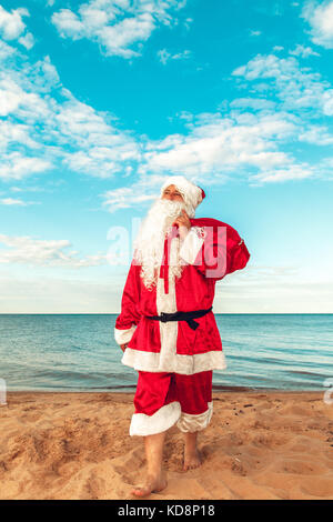 Santa Claus with a bag of gifts on the beach. The symbol of Christmas. Stock Photo