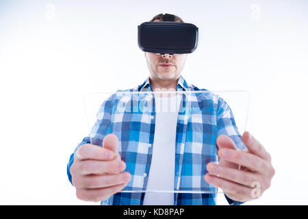 Serious young man holding a tablet in front of him Stock Photo