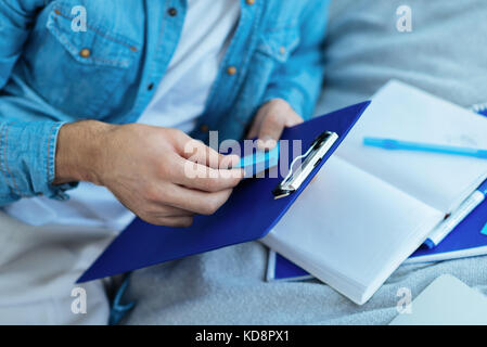 Close up of male hand sticking note on clipboard Stock Photo
