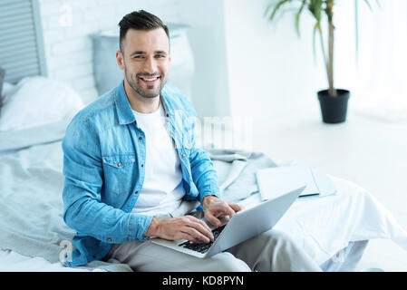 Handsome millennial guy smiling cheerfully into camera Stock Photo