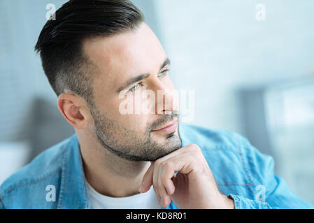 Pensive young man resting his chin on hand while thinking Stock Photo