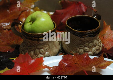 clay cups for morning coffee with green apple in decorated bright autumn foliage Stock Photo
