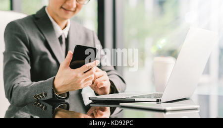 Young businessman or entrepreneur using smartphone, laptop, and digital tablet at work in modern office. Business communication or technology concept Stock Photo