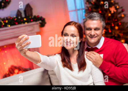 couple taking selfie with christmas tree Stock Photo