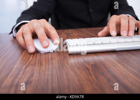 Close-up Of Businessman's Hand Using Computer At Desk Stock Photo