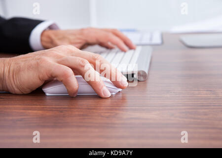 Close-up Of Businessman's Hand Using Computer At Desk Stock Photo
