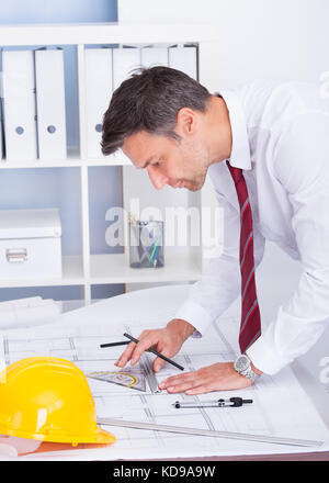 Portrait Of Male Architect Drawing Blueprint In Office Stock Photo