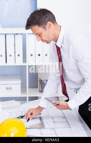Portrait Of Male Architect Drawing Blueprint Using Digital Tablet Stock Photo