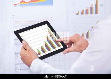 Mature Businessman Analyzing Graph On Digital Tablet Stock Photo