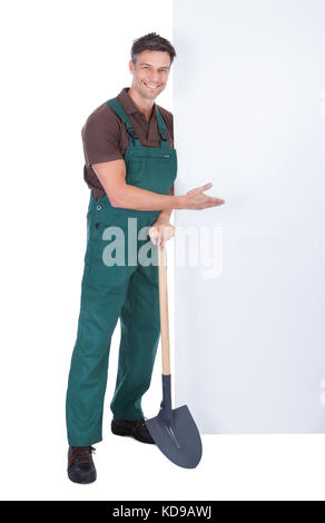 Portrait Of Cheerful Male Gardener With Shovel Presenting Blank Placard ...