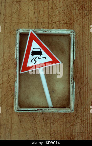 Small box containing model of roadsign with image of car skidding on slippery road Stock Photo
