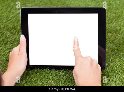 Close-up Of Hand With Digital Tablet On Green Grass Stock Photo