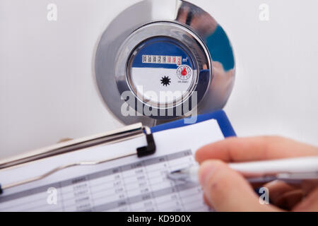 Close-up Of Hand Writing Water Consumption On Paper Sheet With Pen Stock Photo