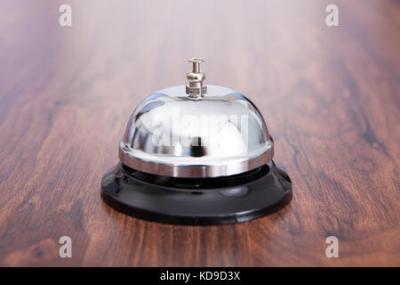 Close-up Of Hand Ringing Service Bell Kept On Wooden Table Stock Photo
