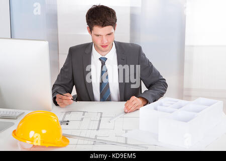 Portrait Of A Young Architect Drawing Plan On Blueprint Stock Photo