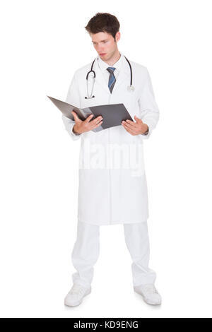 Male Doctor Holding Folder And Reading Medical Reports Stock Photo