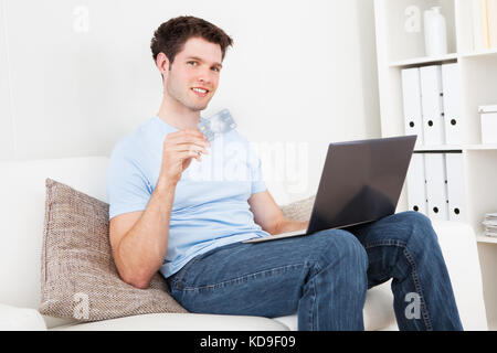 Young Man Sitting With Laptop And Credit Card Shopping Online Stock Photo