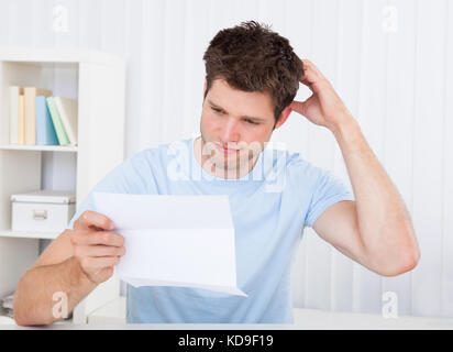 Contemplated Young Man Reading Paper Holding In Hands Stock Photo
