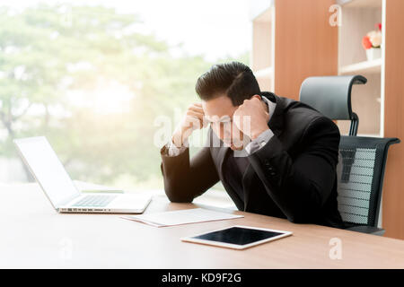 Portrait of tired young Asian business man feeling stress from work. Stress at work and emotional pressure concept. Stock Photo