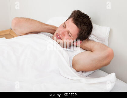 Young Man Suffering From Neckache Lying On Bed Stock Photo