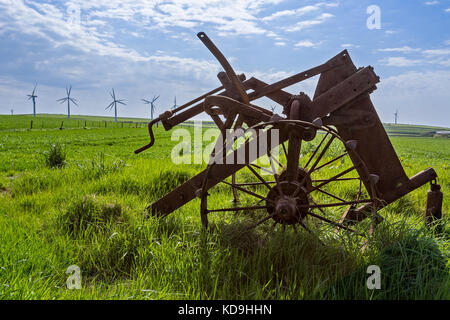 Old and new technology - wind turbines and abandoned plough Stock Photo