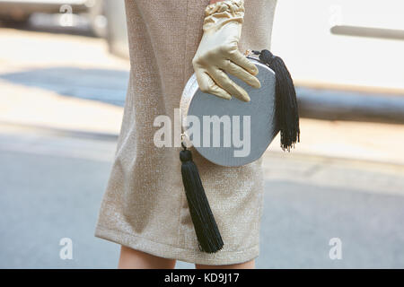 MILAN - SEPTEMBER 21: Woman with silver bag and golden glove before Fendi fashion show, Milan Fashion Week street style on September 21, 2017 in Milan