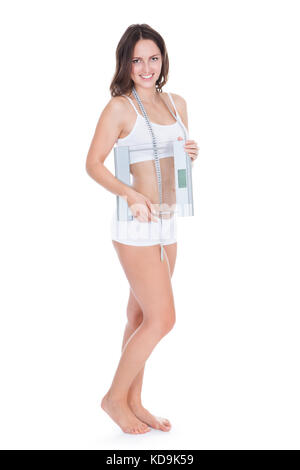 Young Woman With Measurement Tape Around Her Neck Holding Weight Scale Stock Photo