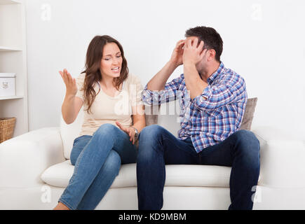 Portrait Of Frustrated Couple Sitting On Couch Quarreling With Each Other Stock Photo