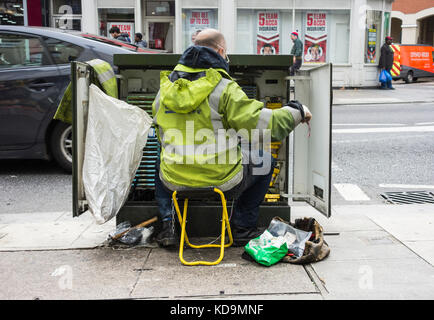 A BT Openreach Telecoms Engineer installing copper wire in a telecoms cabinet in London, U.K. Stock Photo