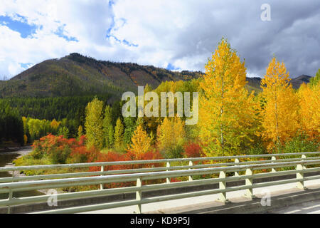 A moutain, fall forest and river from a metal bridge in Glacier National Park. Stock Photo