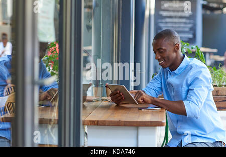 Young African man working online at a sidewalk cafe table Stock Photo