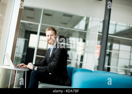 Portrait of redhead smiling young businessman working  on laptop or notebook Stock Photo