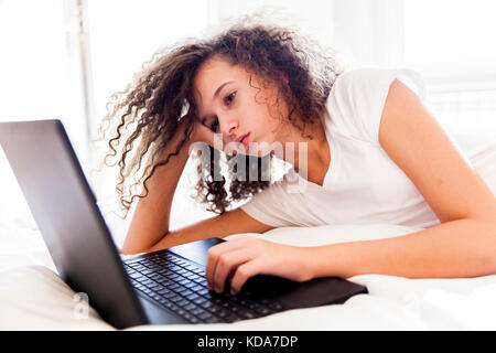 Curly hair teen gitl websurfing internet on laptop at home Stock Photo