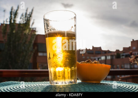 sunset through a glass of beer in the balcony Stock Photo