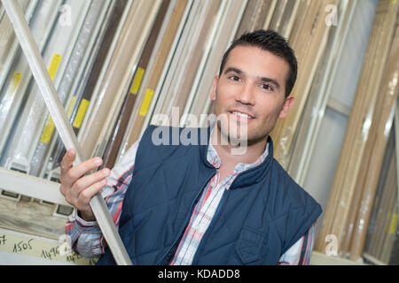 handyman selecting timber from a rack in a hardware Stock Photo